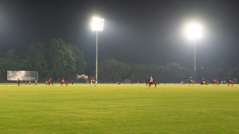 Polo players during a night match under floodlights